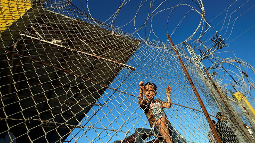 A Palestinian boy stands behind a fence as he waits for his relatives to return to Gaza from Egypt through Rafah border crossing, after it was opened by Egyptian authorities on Wednesday for two days for the first time in three months, in the southern Gaza Strip May 12, 2016. REUTERS/Suhaib Salem           TPX IMAGES OF THE DAY      - RTX2E34K