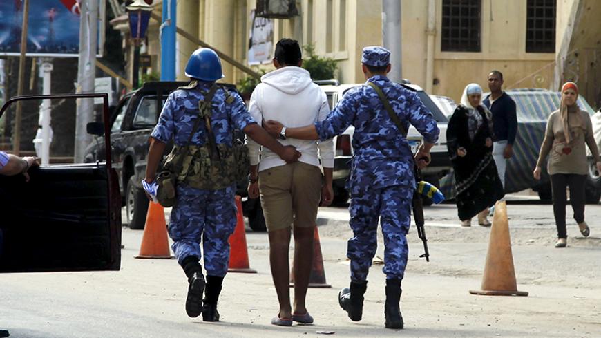 Security forces detain a young man who was holding an electoral advertisement outside a school used as a polling station in Alexandria, Egypt, October 18, 2015. Egypt's long-awaited parliamentary election got off to a slow start on Sunday, marking the final step in a process that was meant to restore democracy but which critics say has been undermined by state repression. REUTERS/Asmaa Waguih - RTS4XVX
