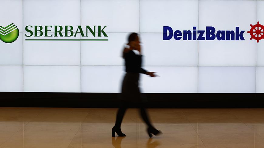 A Denizbank employee walks past by logos of Russia's Sberbank (L) and Turkey's Denizbank at Denizbank headquarters in Istanbul, Turkey March 2, 2016. REUTERS/Murad Sezer ADCO - RTS8YUX
