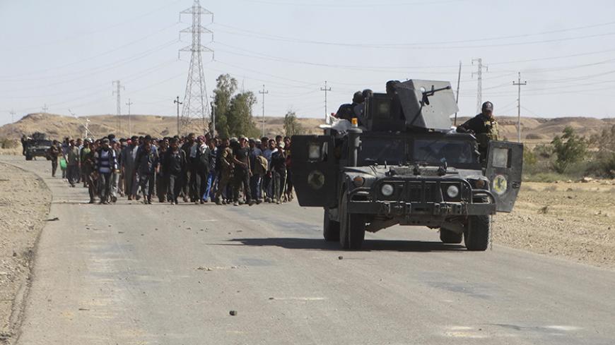 Iraqi security forces escort civilians who fled their homes due to the clashes between Iraqi security forces and Islamic state militants in the town of Hit in Anbar province, April 4, 2016. REUTERS/Stringer TPX IMAGES OF THE DAY - RTSDKA0