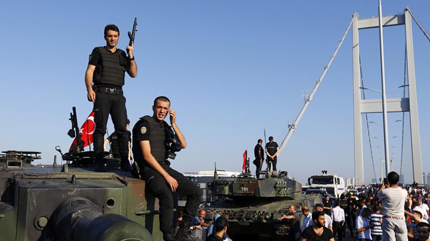 Policemen stand atop military armored vehicles after troops involved in the coup surrendered on the Bosphorus Bridge in Istanbul, Turkey July 16, 2016.   REUTERS/Murad Sezer  - RTSI8W9