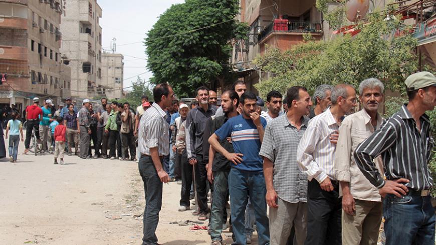 Residents and Palestinians who fled the Yarmouk refugee camp wait in line to receive parcels of humanitarian aid from the United Nations Relief and Works Organization (UNRWA) in the beseiged southern outskirts of Damascus May 23, 2015. REUTERS/Ward Al-Keswani - RTX1E8VS