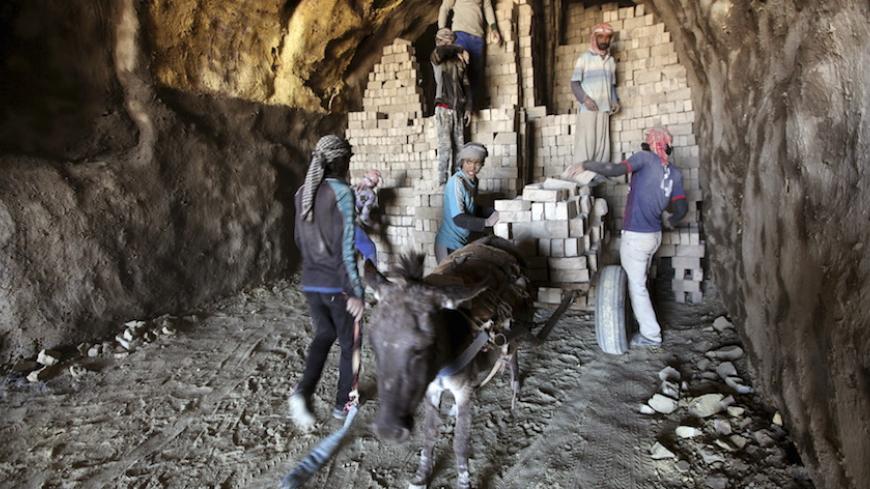 Iraqi workers load bricks on a donkey-drawn cart in a brick factory in Najaf, Iraq, February 9, 2016.  REUTERS/Alaa Al-Marjani  - RTX266RY