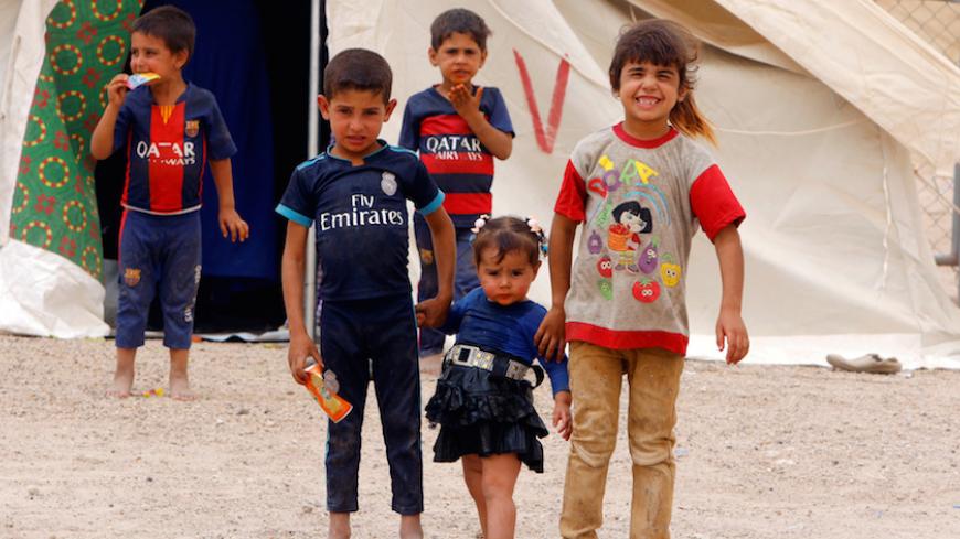 Displaced Iraqi children, who fled from Falluja because of Islamic State violence, pose for photographer during a dust storm at a refugee camp in Ameriyat Falluja, south of Falluja, Iraq, June 16, 2016. REUTERS/Ahmed Saad - RTX2GM7G