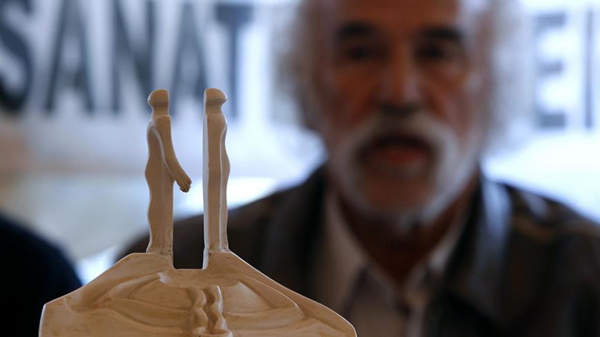 Turkish artist Mehmet Aksoy is seen behind a model of his sculpture during a news conference in Istanbul January 12, 2011. The fate of a giant peace monument symbolising reconciliation between Turks and Armenians has caused a row in Turkey after Prime Minister Tayyip Erdogan branded it "monstrous" and called for its demolition. The unfinished monument by renowned Turkish sculptor Aksoy consists of two concrete figures more than 30 metres high who face each other on an hill in the northeastern city of Kars.