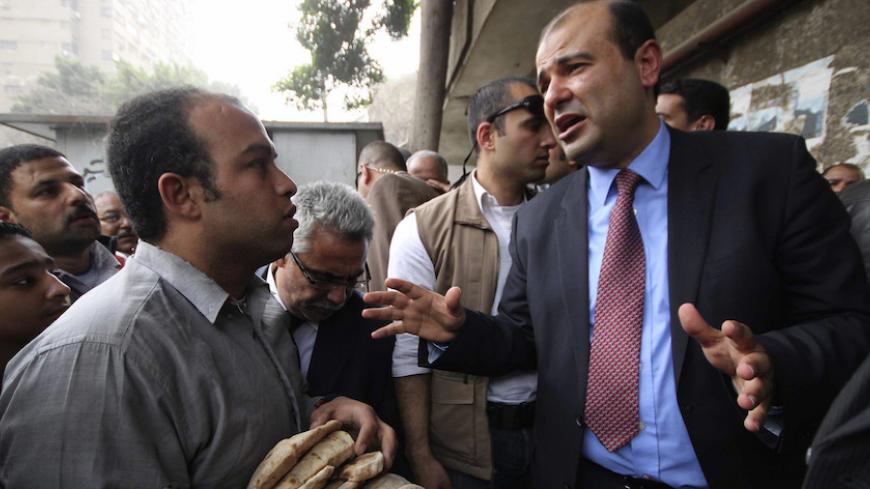 Egypt's new Supplies Minister Khaled Hanafi (R) talks during a tour at bakeries in Cairo March 2, 2014. Egypt's new supplies minister said he would reconsider a decision to halt rice exports and look into French wheat imports which were excluded after Egypt changed its specification concerning wheat moisture levels, state media reported on Sunday. REUTERS/Al Youm Al Saabi Newspaper (EGYPT - Tags: POLITICS BUSINESS COMMODITIES FOOD) - RTR3FWPB
