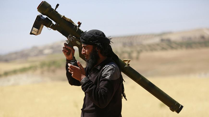 An Islamist Syrian rebel group Jabhat al-Nusra fighter talks on a walkie-talkie while carrying his weapon on Al-Khazan frontline of Khan Sheikhoun, northern Idlib province May 17, 2014. REUTERS/Hamid Khatib (SYRIA - Tags: CIVIL UNREST MILITARY POLITICS CONFLICT) - RTR3PMA6
