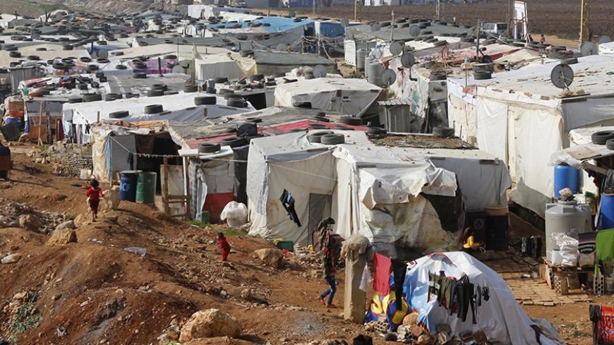 Syrian refugees walk at a refugee camp in Zahle in the Bekaa valley November 18, 2014. In October, Lebanon, which has the highest per capita concentration of refugees in the world at one in four residents, said it could not cope with more than one million Syrians and has asked for funds to help look after them. REUTERS/Mohamed Azakir (LEBANON - Tags: CIVIL UNREST SOCIETY IMMIGRATION POVERTY) - RTR4EK8N