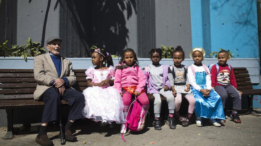 Students wearing costumes sits on a bench next to an elderly man during a parade for the upcoming Jewish holiday of Purim outside the Bialik Rogozin school in Tel Aviv March 3, 2015. At Bialik Rogozin, children of migrant workers and refugees are educated alongside native Israelis. Purim is a celebration of the Jews' salvation from genocide in ancient Persia, as recounted in the Book of Esther. REUTERS/Amir Cohen (ISRAEL - Tags: RELIGION SOCIETY EDUCATION) - RTR4RVY9