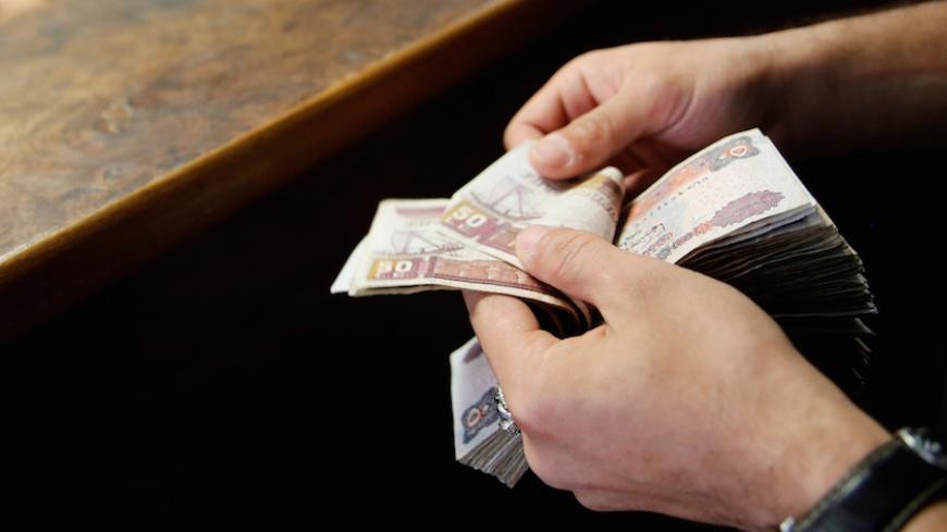 A customer counts his Egyptian 50 pound notes at an exchange office in downtown Cairo, Egypt, April 19, 2016. REUTERS/Amr Abdallah Dalsh - RTX2GCMQ