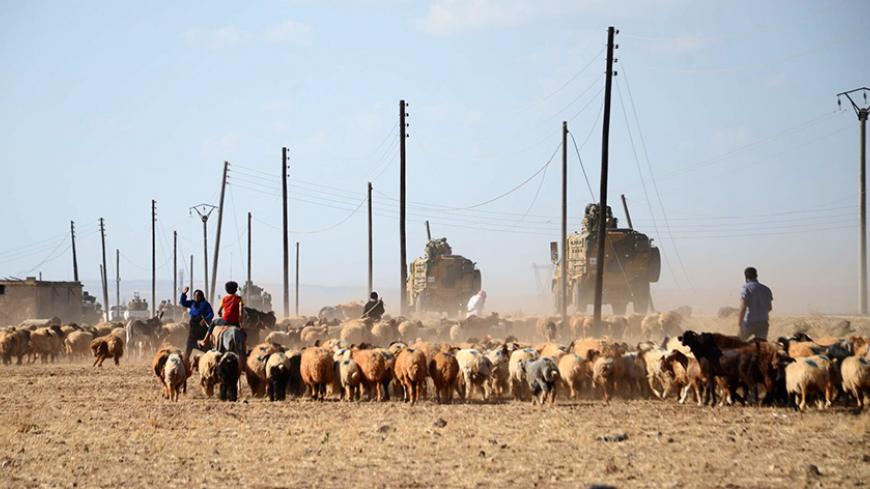 TOPSHOT - Turkish troops drive their anti-mine Armoured Personnel Carrier (APC) past shepherds on September 4, 2016 on a road near the Syrian village of Tuwairan, located around 2km of al-Rai, the small border town with Turkey. 
Turkish forces and Syrian rebels expelled the Islamic State group from the last areas of the Syrian-Turkish border under their control on September 3, 2016, the Syrian Observatory for Human Rights said. / AFP / Nazeer al-Khatib        (Photo credit should read NAZEER AL-KHATIB/AFP/G