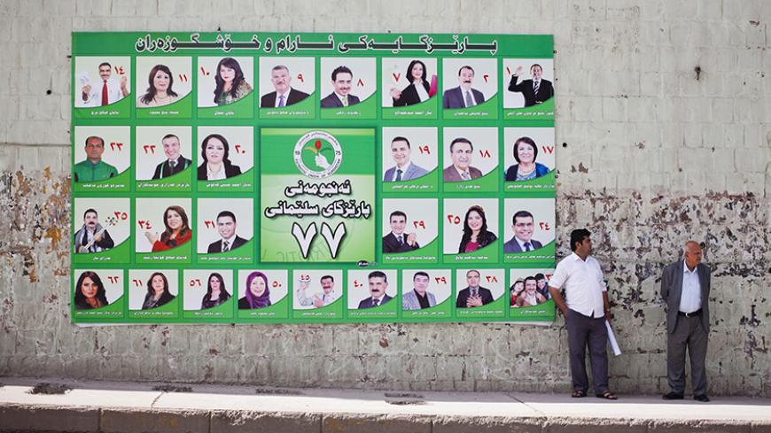 Men stand next to a Patriotic Union of Kurdistan (PUK) campaign poster for Iraq's parliamentary elections in Sulaimaniya April 28, 2014. Picture taken April 28, 2014. To match IRAQ-ELECTION/KURDS REUTERS/Jacob Russell (IRAQ - Tags: ELECTIONS POLITICS) - RTR3N0GT