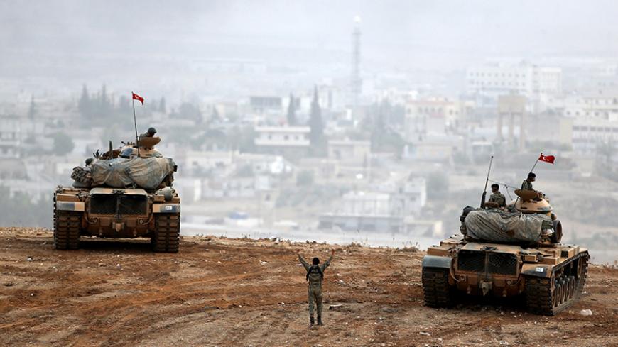 Turkish army tanks take position on top of a hill near Mursitpinar border crossing in the southeastern Turkish town of Suruc in Sanliurfa province, Turkey, October 11, 2014. REUTERS/Umit Bektas/File photo  - RTSJOQM