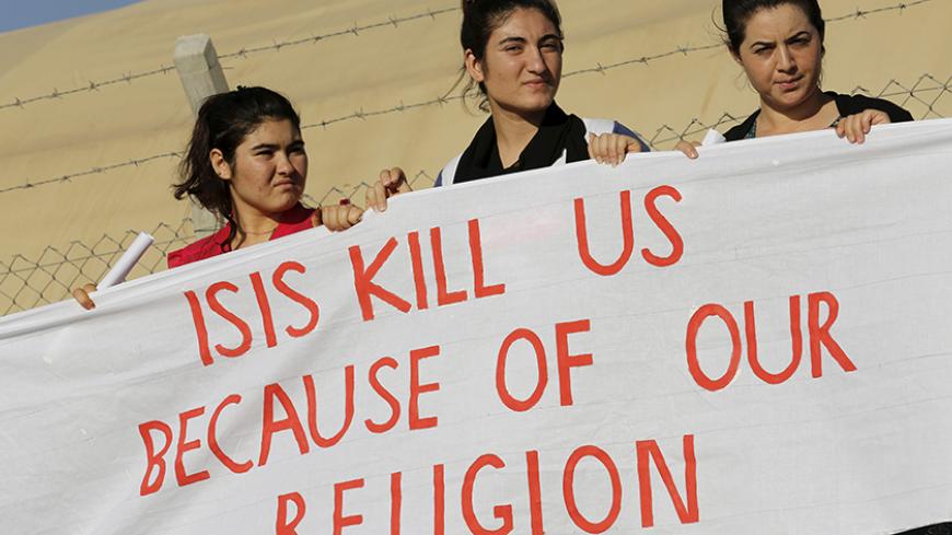 Yazidi refugee women stand behind a banner as they wait for the arrival of United Nations High Commissioner for Refugees Special Envoy Angelina Jolie at a Syrian and Iraqi refugee camp in the southern Turkish town of Midyat in Mardin province, Turkey, June 20, 2015. REUTERS/Umit Bektas - RTX1HE42