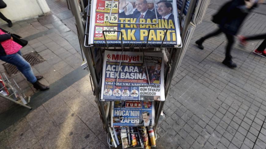People walk past by a kiosk in central Istanbul, Turkey November 2, 2015. A jubilant President Tayyip Erdogan on Monday cast the return of Turkey's Islamist-rooted AK Party to single-party rule as a vote for stability that the world must respect, but opponents fear it heralds growing authoritarianism and deeper polarisation. The newspaper headline on top reads: "AK Party on its own" REUTERS/Murad Sezer - RTX1UE7G