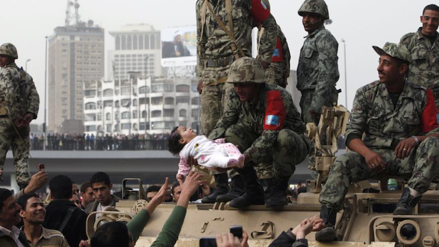A protester reaches out as a soldier holds a child during a demonstration in Cairo January 29, 2011. Thousands of angry Egyptians rallied in central Cairo on Saturday to demand that Egypt's President Hosni Mubarak resign, dismissing his offer of dialogue and calling on troops to come over to their side. REUTERS/Asmaa Waguih (EGYPT - Tags: CIVIL UNREST MILITARY POLITICS SOCIETY) - RTXX8TU