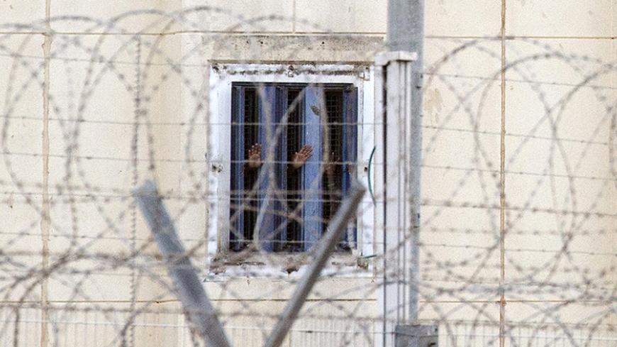 Prisoners gesture from their cell at HaSharon (Rimonim) high security prison, some 40 kilometers northeast of Tel Aviv, on February 23, 2014, after an American-Israeli prisoner serving life for murder was shot dead after he seized a gun and opened fire on three guards, before barricading himself in a prison bathroom. Samuel Sheinbein was killed when elite troops entered the bathroom at Rimonim prison to bring the situation to an end. AFP PHOTO / JACK GUEZ        (Photo credit should read JACK GUEZ/AFP/Getty