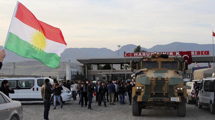 A man waves a Kurdistan flag as a Turkish military truck escorts a convoy of peshmerga vehicles at Habur border gate, which separates Turkey from Iraq, near the town of Silopi in southeastern Turkey, October 29, 2014. Iraqi peshmerga fighters arrived in southeastern Turkey early on Wednesday ahead of their planned deployment to the Syrian town of Kobani to help fellow Kurds repel an Islamic State advance, a Reuters witness said. REUTERS/Kadir Baris (TURKEY - Tags: POLITICS MILITARY CONFLICT TPX IMAGES OF TH