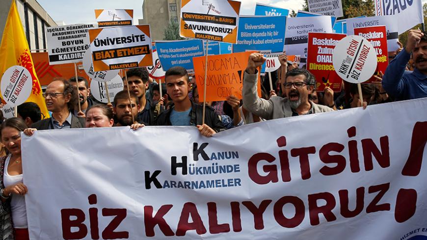 Demonstrators hold signs in front of the High Education Board (YOK) during a protest against the suspension of academics from universities following a post-coup emergency decree, in Ankara, Turkey, September 22, 2016. The sign in the foreground reads "Let the emergency decrees go. We are remaining." REUTERS/Umit Bektas - RTSOY0Z