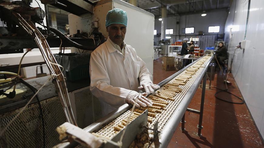 A worker stands near a conveyor belt at a chocolate and baked goods factory in the West Bank city of Ramallah October 27, 2013. The crackdown on the Gaza Strip as Egypt demolishes the smuggling tunnels along its sandy border, and stagnation in the West Bank mean the Palestinian economy might shrink this year after average annual growth of about nine percent in 2008-2011. To match Analysis PALESTINIANS-ECONOMY/ REUTERS/Mohamad Torokman (WEST BANK - Tags: POLITICS BUSINESS FOOD) - RTX14QCR