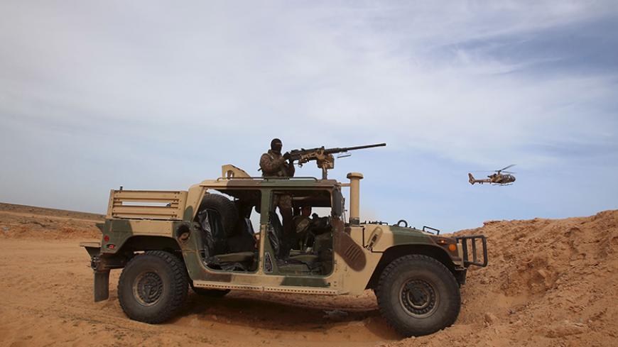 A Tunisian soldier holds his position during an exercise along the frontier with Libya in Sabkeht Alyun, Tunisia February 6, 2016. Tunisia has completed a 200-km (125 mile) barrier along its frontier with Libya to try to keep out Islamist militants, and will soon install electronic monitoring systems, Defence Minister Farhat Hachani said on Saturday. REUTERS/Zoubeir Souissi      TPX IMAGES OF THE DAY      - RTX25SC1