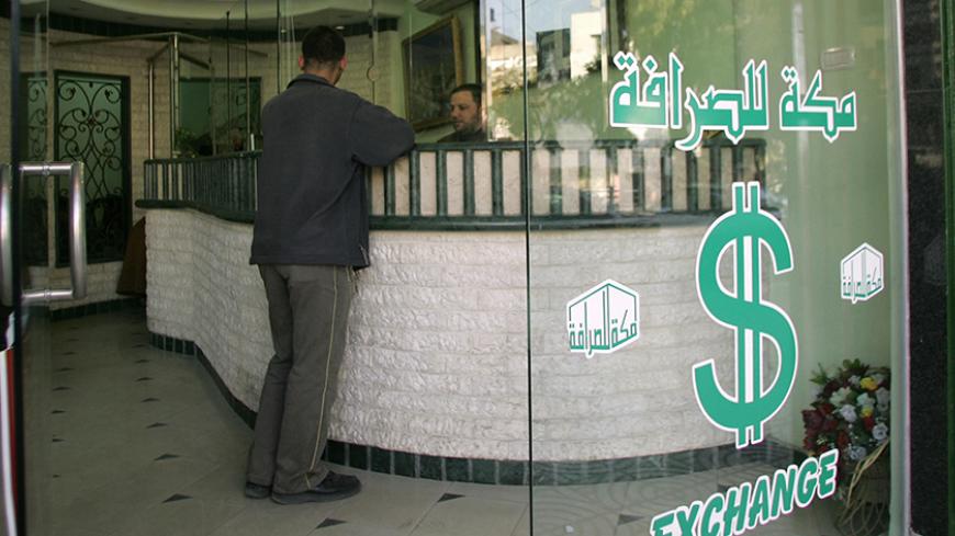 GAZA CITY, -:  A Palestinian man changes money at a currency exchange bureau in Gaza City 30 January 2006. Hamas today sought to reassure investors in the Palestinian economy that their stocks would be safe under the Muslim fundamentalist group after it shot to power in last week's general election. AFP PHOTO/MAHMUD HAMS  (Photo credit should read MAHMUD HAMS/AFP/Getty Images)