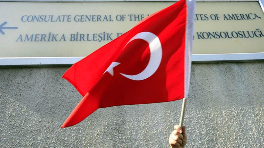 A protester holds a Turkish flag under a sign of the U.S. consulate in Istanbul, during a demonstration against the U.S. policy over northern Iraq as well as the killing of Turkish soldiers by PKK Kurdish rebels in southeast Turkey, October 26, 2007. Turkish helicopters ferried more troops to the border with Iraq on Friday as diplomatic efforts got under way in Ankara to avert a major offensive against Kurdish guerrillas based in northern Iraq. REUTERS/Fatih Saribas (TURKEY) - RTR1VCO0