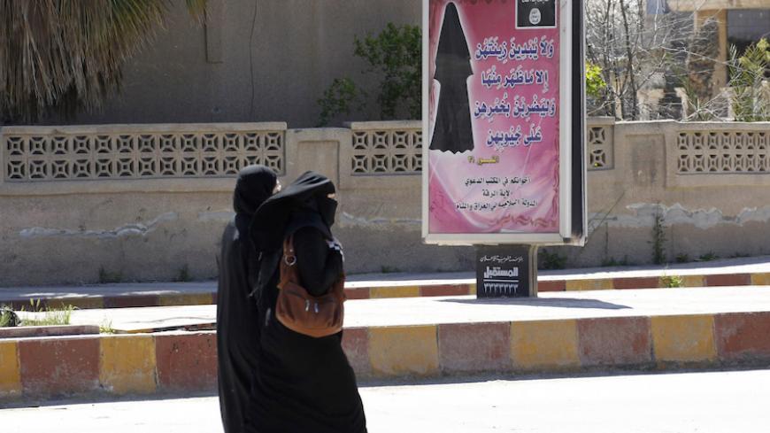 Veiled women walk past a billboard that carries a verse from Koran urging women to wear a hijab in the northern province of Raqqa March 31, 2014. The Islamic State in Iraq and the Levant (ISIL) has imposed sweeping restrictions on personal freedoms in the northern province of Raqqa. Among the restrictions, Women must wear the niqab, or full face veil, in public or face unspecified punishments "in accordance with sharia", or Islamic law. REUTERS/Stringer   (SYRIA - Tags: POLITICS CIVIL UNREST CONFLICT RELIGI