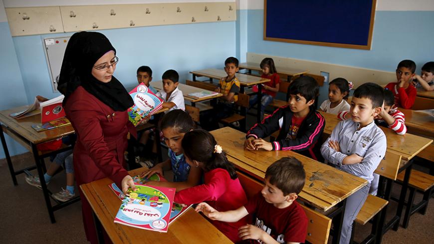 A Syrian refugee teacher distributes books to her refugee students in their classroom at Fatih Sultan Mehmet School in Karapurcek district of Ankara, Turkey, September 28, 2015. Out of 640,000 Syrian children in Turkey, 400,000 are not at school, a Turkish official told Reuters on Friday, warning that those who miss out are likely to be exploited by "gangs and criminals". Educating the children among more than 2.2 million Syrian refugees in Turkey - most of whom live outside purpose-built camps - is seen as