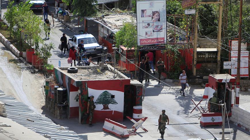 People walk past a Lebanese army checkpoint at the entrance to Ain al-Hilweh camp Palestinian refugee camp near Sidon, South Lebanon September 22, 2016. REUTERS/Ali Hashisho - RTSP03P