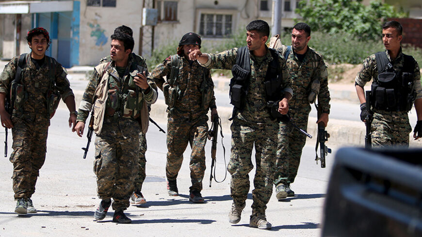 Kurdish fighters from the People's Protection Units (YPG) walk along a street in the southeast of Qamishli city, Syria, April 22, 2016. REUTERS/Rodi Said - RTX2B6V4