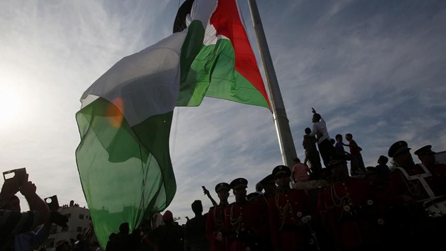 People watch the raising of a Palestinian flag during a rally marking the Palestinian Declaration of Independence in 1988, in the West Bank city of Tulkarm November 14, 2016. REUTERS/Abed Omar Qusini - RTX2TLI1