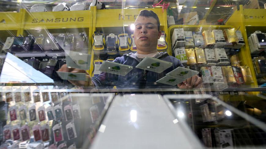 A Palestinian man displays SIM cards of Palestinian Jawwal cellular company in a mobile phone shop in Gaza City November 16, 2016. REUTERS/Ibraheem Abu Mustafa  - RTX2U31Z
