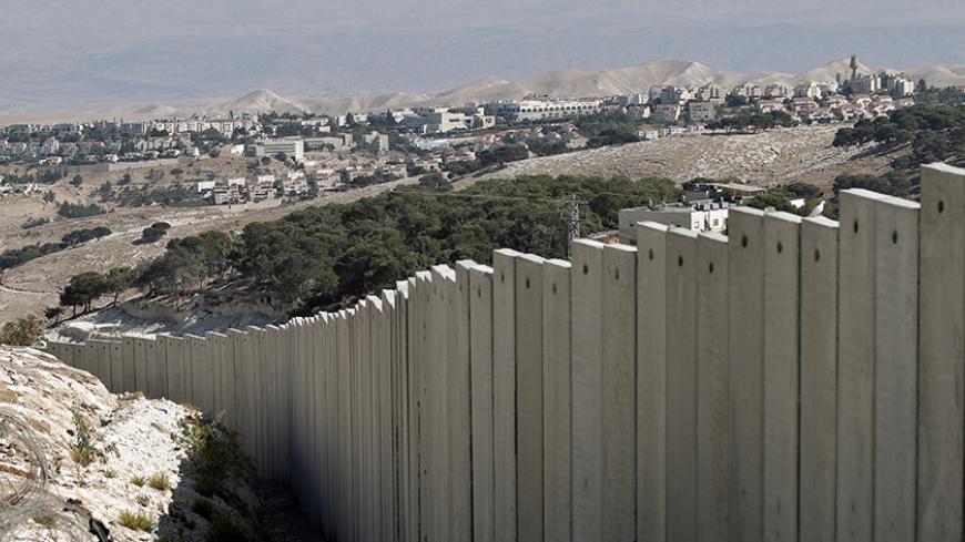 A picture taken on October 21, 2014 in the West Bank village of Zayem near Jerusalem, shows the Israel's controversial separation barrier with the Jewish settlement of Maale Adumim in the background. AFP PHOTO/AHMAD GHARABLI (Photo credit should read AHMAD GHARABLI/AFP/Getty Images)
