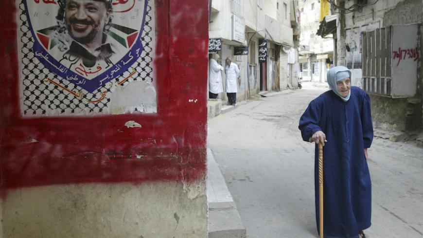 A Palestinian woman walks past an image of Yasser Arafat in Shatila refugee camp near Beirut May 23, 2007. The Lebanese army is trying to crush Fatah al-Islam, a militant group led by a Palestinian but with little or no support among Lebanon's Palestinian refugee population of 400,000. Dozens of people have died in three days of fighting. REUTERS/Sharif Karim (LEBANON) - RTR1Q090