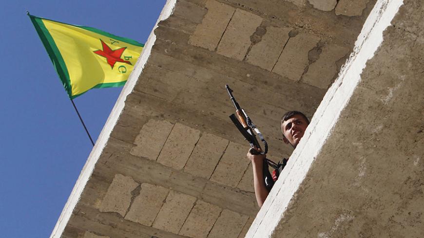 A Kurdish fighter from the Popular Protection Units (YPG) holds his weapon as he takes position atop a building with a YPG flag in Aleppo's Sheikh Maqsoud neighbourhood, June 7, 2013. Kurdish fighters from the YPG joined the Free Syrian Army to fight against forces loyal to Syria's President Bashar al-Assad. Picture taken June 7, 2013. REUTERS/Muzaffar Salman  (SYRIA - Tags: CIVIL UNREST POLITICS CONFLICT) - RTX10USX