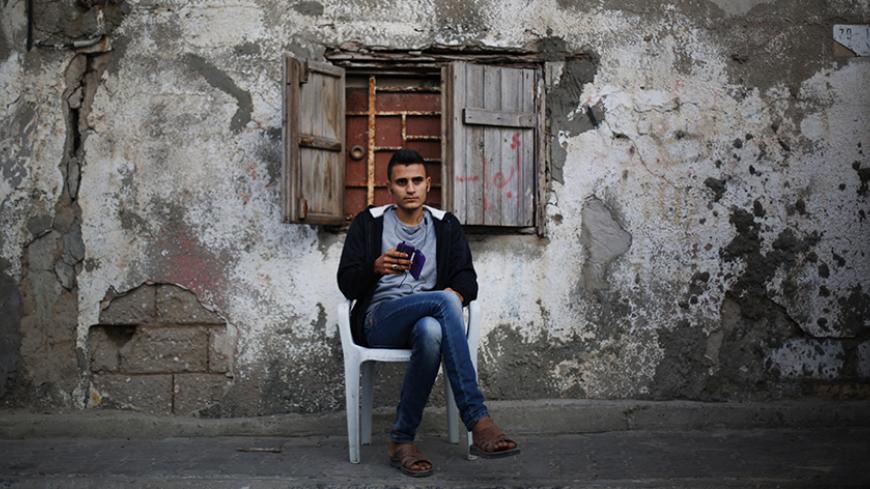 A Palestinian man plays with his mobile the Shati refugee camp in Gaza City on April 13, 2014. AFP PHOTO/MOHAMMED ABED (Photo credit should read MOHAMMED ABED/AFP/Getty Images)