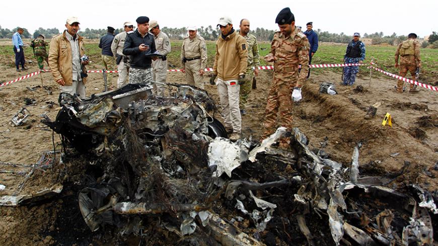 Iraqi security forces stand next to burnt car at the site of an attack on a police checkpoint, near the town of Qadisiyah, 40km south of the Iraqi holy Shiite city of Najaf on January 1, 2017.
Gunmen wearing suicide vests and driving an explosives-laden vehicle opened fire on the checkpoint near the town of Qadisiyah, which lies around 180 kilometres (110 miles) south of Baghdad. / AFP / Haidar HAMDANI        (Photo credit should read HAIDAR HAMDANI/AFP/Getty Images)