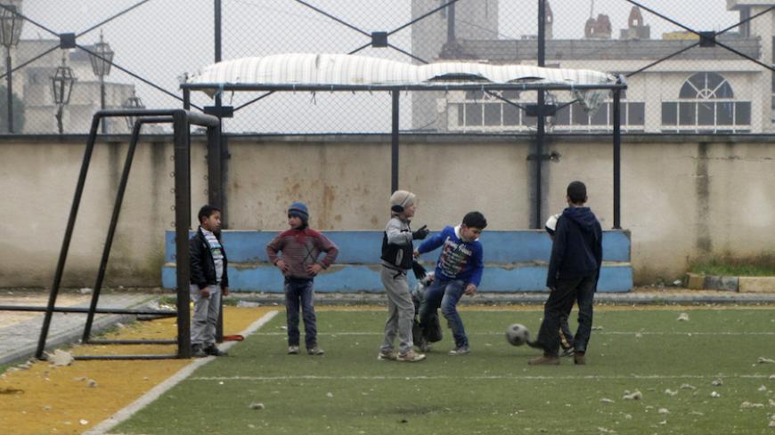 Children play soccer at a playground in the northwestern Homs district of Al Waer January 17, 2015. U.N. aid workers have started delivering food to tens of thousands of people trapped in a besieged district of Homs city in Syria following negotiations with warring parties, officials said on Friday. . REUTERS/Stringer (SYRIA - Tags: SOCIETY) - RTR4LTIK
