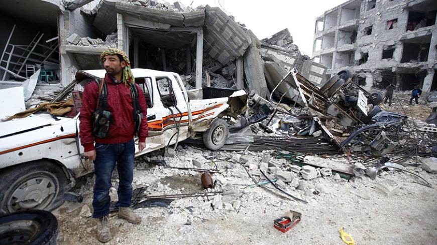 A fighter of the Kurdish People's Protection Units (YPG) stands next to damaged buildings in the northern Syrian town of Kobani January 30, 2015. Sheets meant to hide residents from snipers' sights still hang over streets in the Syrian border town of Kobani, and its shattered buildings and cratered roads suggest those who fled are unlikely to return soon. Kurdish forces said this week they had taken full control of Kobani, a mainly Kurdish town near the Turkish border, after months of bombardment by Islamic