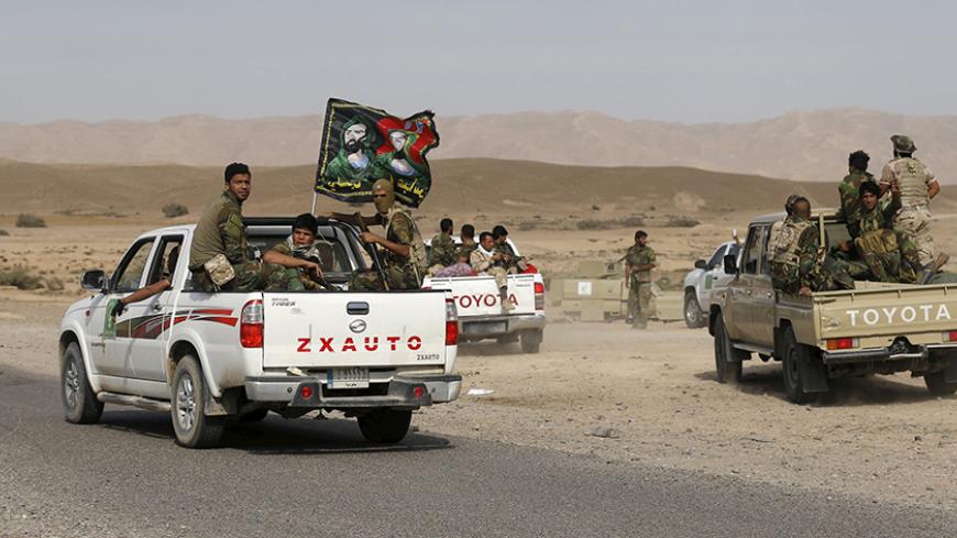 Shi'ite fighters ride on the back of a truck with their weapons in al-Fatha, northeast of Baiji, October 18, 2015. Iraqi forces backed by Shi'ite militia fighters say they have retaken a mountain palace complex of former President Saddam Hussein from Islamic State fighters, as government forces push ahead on a major offensive against the insurgents.   REUTERS/Thaier Al-Sudani  - RTS4Z28