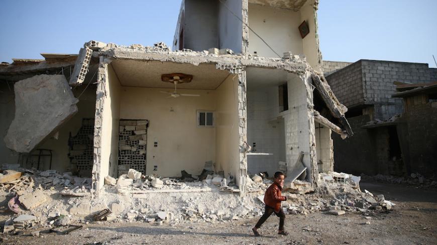 A boy runs near damaged buildings in the rebel held besieged city of Douma, in the eastern Damascus suburb of Ghouta, Syria January 19, 2017. REUTERS/Bassam Khabieh     TPX IMAGES OF THE DAY - RTSWBM4