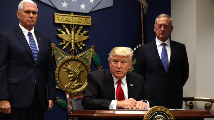 U.S. President Donald Trump signs an executive order to impose tighter vetting of travelers entering the United States, at the Pentagon in Washington, U.S., January 27, 2017. The executive order signed by Trump imposes a four-month travel ban on refugees entering the United States and a 90-day hold on travelers from Syria, Iran and five other Muslim-majority countries. Picture taken January 27, 2017. REUTERS/Carlos Barria - RTSXWM6