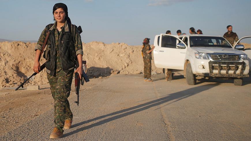 A female member of the Sinjar Resistance Units (YBS), a militia affiliated with the Kurdistan Workers' Party (PKK), carries a sniper and an AK-47 rifle in the village of Umm al-Dhiban, northern Iraq, April 29, 2016. They share little more than an enemy and struggle to communicate on the battlefield, but together two relatively obscure groups have opened up a new front against Islamic State militants in a remote corner of Iraq. The unlikely alliance between the Sinjar Resistance Units, an offshoot of a lefti