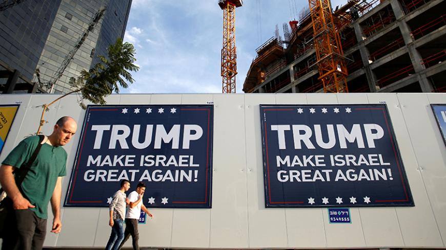 People walk past signs bearing the name of U.S. President-elect Republican Donald Trump in Tel Aviv, Israel November 14, 2016. REUTERS/Baz Ratner - RTX2TLRV
