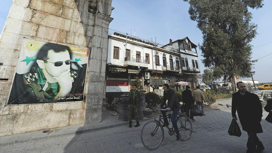 People walk past a picture of Syria's President Bashar al-Assad at Bab Sharqi entrance, near the Jobar district of Damascus, Syria, January 5, 2017. REUTERS/Omar Sanadiki - RTX2XN2D