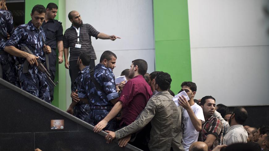 Palestinian employees of the former Hamas government queue up outside a post office in Gaza City on October 29, 2014 to receive 1,200 US dollars each, which is part of their wages that has been delayed for months. The Palestinian national unity government headed by prime minister Rami Hamdallah sent the previous day roughly 30 million dollars by car across the Erez border crossing from the West Bank to the Gaza Strip to pay 24,000 former employees. AFP PHOTO / MAHMUD HAMS        (Photo credit should read MA