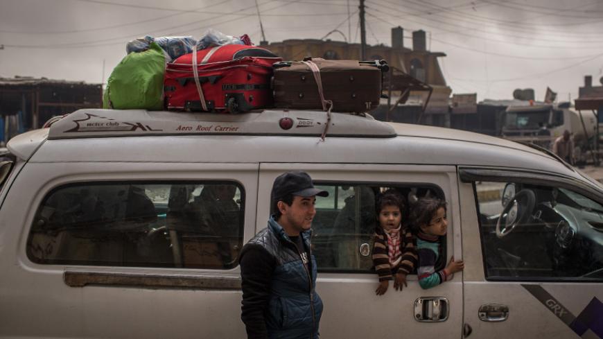 AL QAYYARAH, IRAQ - NOVEMBER 10:  A family returning home waits to pick up supplies from a store under smoke filled skies from burning oil wells set on fire by fleeing ISIS members on November 10, 2016 in Al Qayyarah, Iraq. Many families have begun returning to their homes in recently liberated towns south of Mosul. Oil wells in the area that were set on fire by ISIS continue to burn blanketing the area in think clouds of smoke and oil.  (Photo by Chris McGrath/Getty Images)