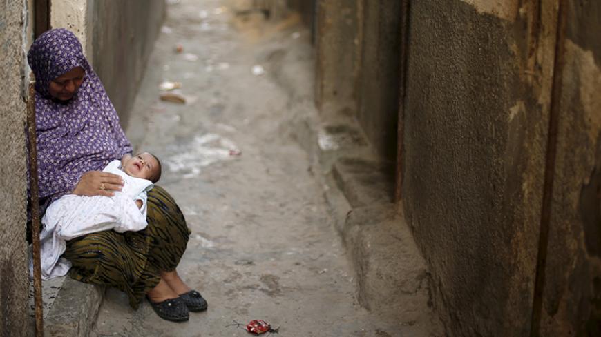 A Palestinian woman holds her grandchild as she sits at the entrance of her house to escape the heat during a power cut at Shatti (beach) refugee camp in Gaza City September 15, 2015. Power has been provided to different areas in the impoverished coastal territory in six-hour shifts as Gaza's lone power plant shut its generators on Saturday due to a fuel shortage, energy officials said. Electricity is also supplied to the Gaza grid through power lines from Israel and Egypt. Gaza's plant provides electricity