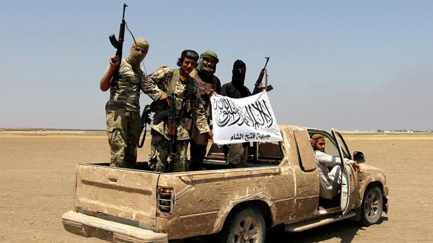 FILE PHOTO: Fighters of the Syrian Islamist rebel group Jabhat Fateh al-Sham cheer on a pickup truck after a Russian helicopter was shot down in the north of Syria's rebel-held Idlib province, Syria, August 1, 2016. REUTERS/Ammar Abdullah/File Photo - RTSWG1A